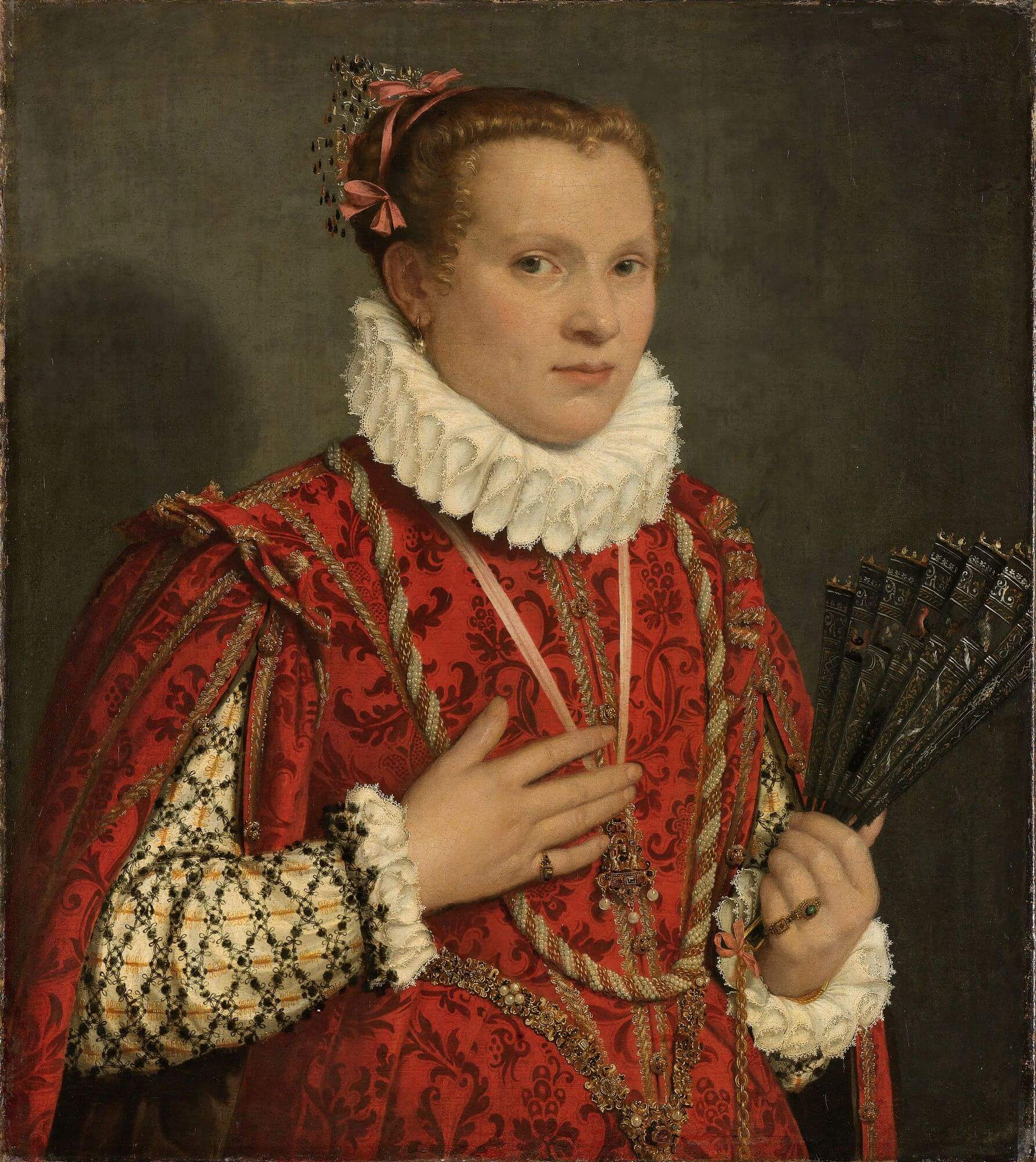 Kobieta w wytwornym czerwonym stroju, z białą kryzą, trzymająca wachlarz w lewej dłoni.