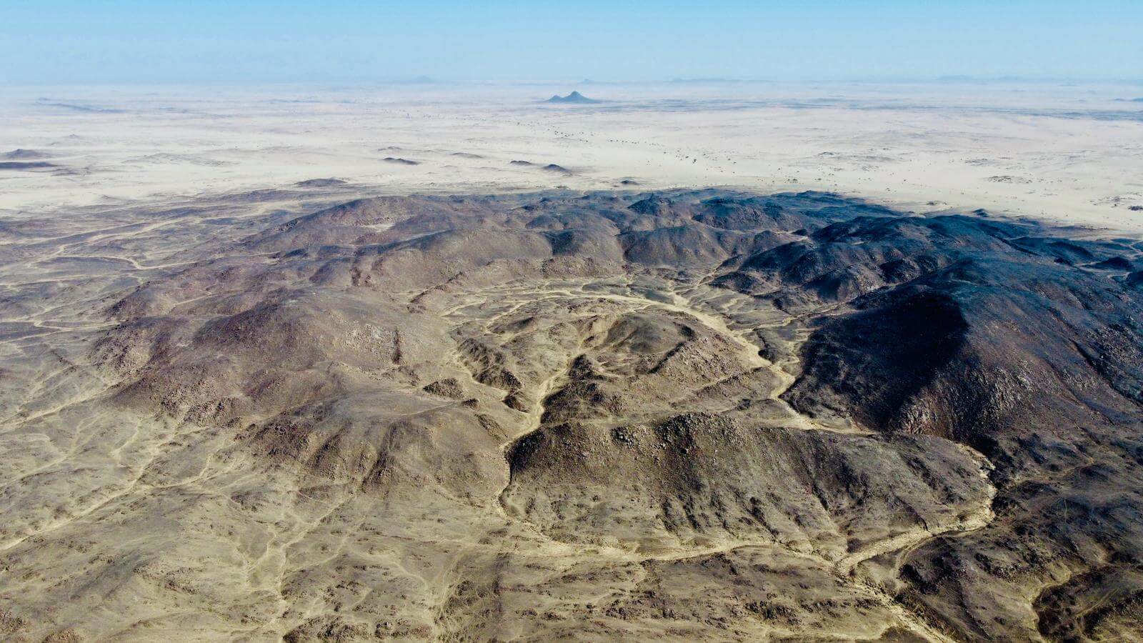 Zdjęcie z perspektywy ptasiej przedstawia krater powulkaniczny na afrykańskiej pustyni.
